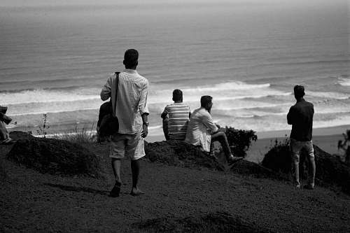 human grayscale photo of person walking and facing the seashore black-and-white