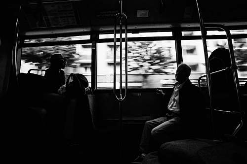 person grayscale photo of several people on moving train black-and-white