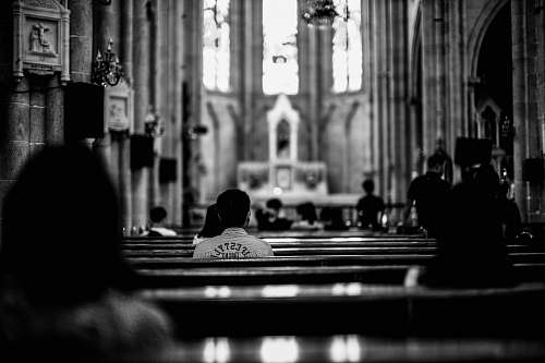 person grayscale photo of wooden pew black-and-white