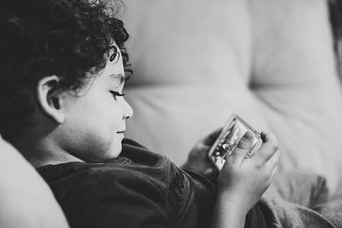 person grayscale photography of child lying on bed black-and-white