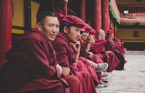 human group of men wearing red dress sitting at the temple smiling while taking selfie person