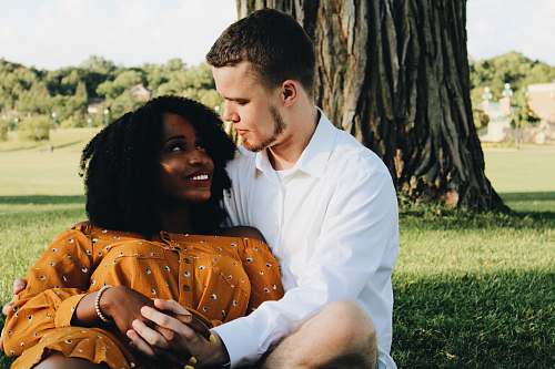 person man and woman hugging while sitting on lawn grass human