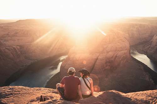 human man and woman sitting on rock formation couple