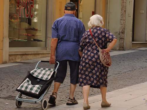 human man and woman walking on street with stroller person