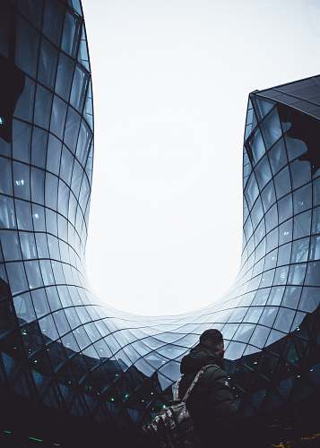 person man carrying backpack white standing in front of glass building human