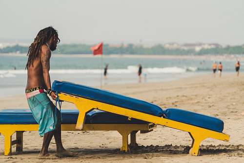 person man carrying sunlounger chair sea
