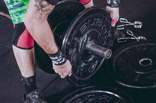human man holding black Rogue weight plate person