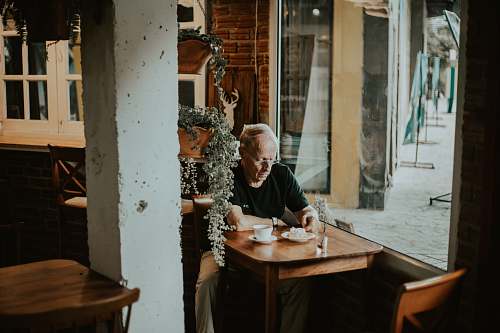 human man in black shirt sits inside restaurant with coffee on front person