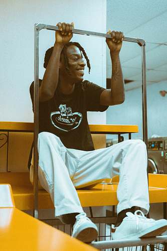 human man in black T-shirt and white pants sitting on table holding stainless steel bar person