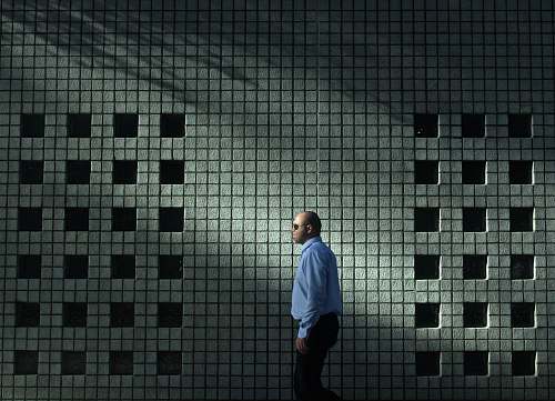 human man in blue dress shirt walking near gray concrete wall person