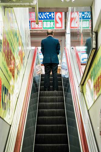 person man in blue suit jacket standing on escalator human