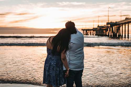 human man in dress shirt beside woman in dress pier