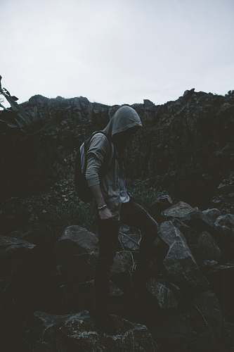 human man in hoodie stepping on rocks person