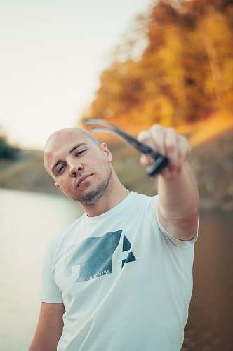 human man in white crew-neck T-shirt holding sunglasses person