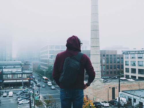 person man looking down the city covered with fogs during daytime human