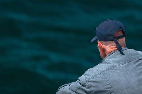 human man looking on body of water wearing black cap person