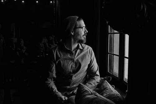 person man looking through glass window black-and-white