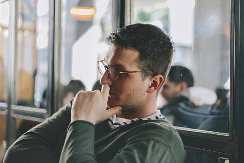 human man sitting and leaning on clear glass wall person