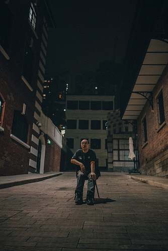 human man sitting on chair between brown brick buildings person