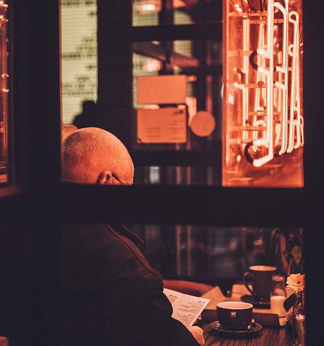 person man sitting on chair reading book in front of table cup