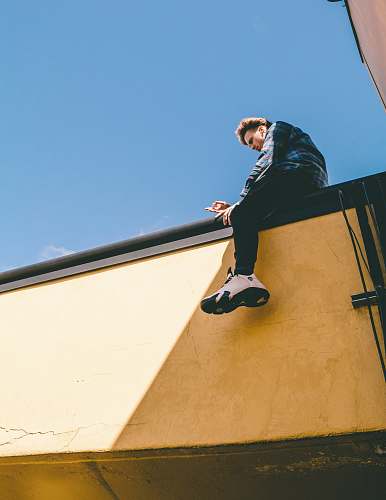 human man sitting on roof under blue sky person