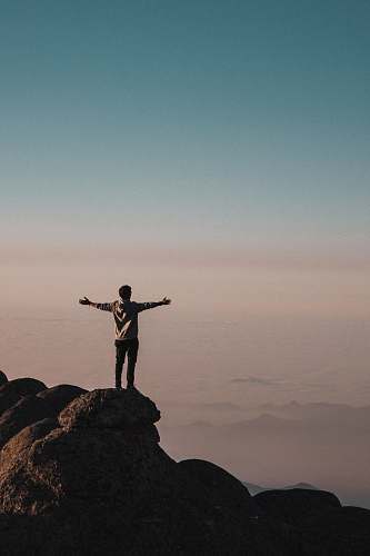 human man standing beside cliff person