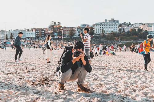 person man taking photo on white sand beach human