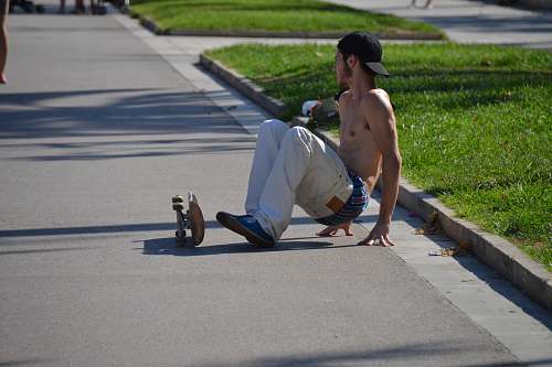 human man using skateboard beside green grasses during daytime person