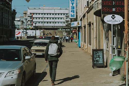 human man walking along sidewalk during daytime person