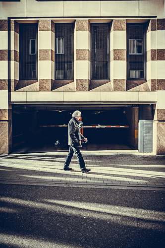 person man walking on pavement in front of concrete structure human