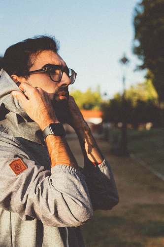 human man wearing black framed eyeglasses fixing hood person