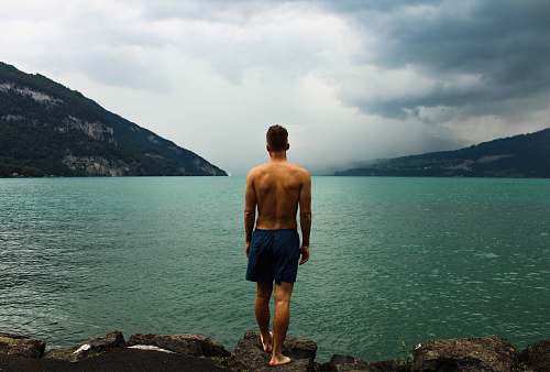 person man wearing black shorts standing in front of body of water switzerland