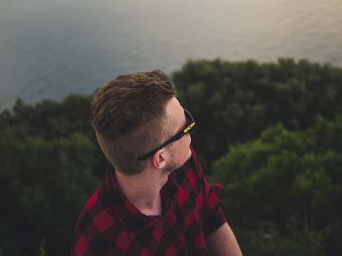 human man wearing black sports sunglasses facing body of water person
