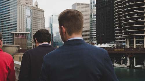human man wearing blue blazer standing behind two men during daaytime person