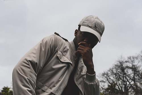human man wearing gray jacket and cap under the gray clouds person