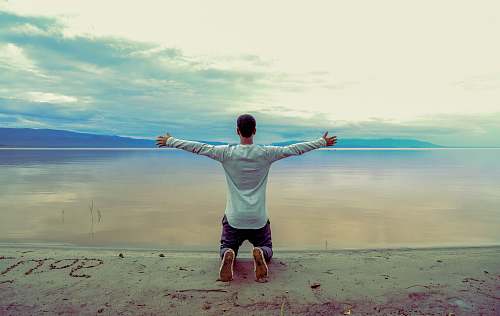 human man wearing gray long-sleeved shirt beside seashore during daytime person