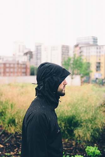 person man wearing hoodie standing near grass with building background during daytime manchester