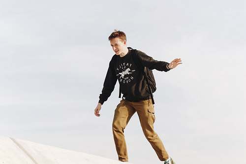 human man wearing long-sleeved shirt and khaki pants on top of roof person