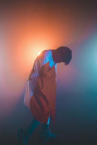 person man wearing white and orange long-sleeved shirt standing near orange light human