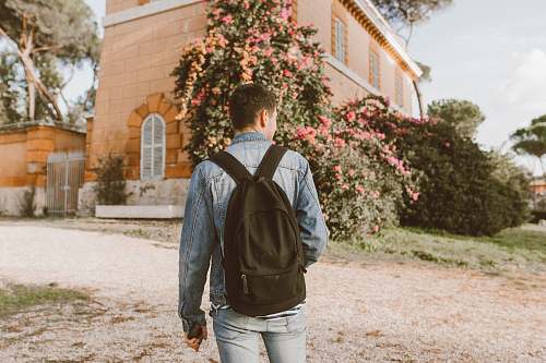 person man with backpack standing in front of a house plant