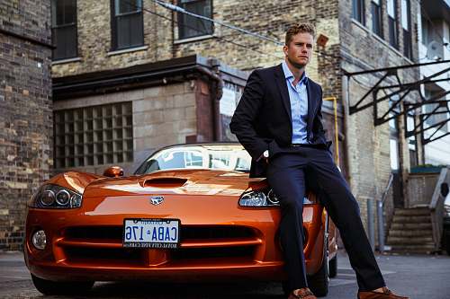 person men's black suit and orange coupe car