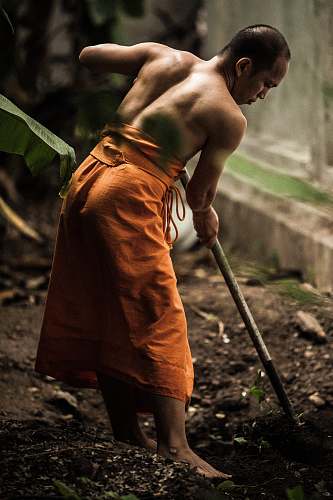 human monk gardening near grey wall person