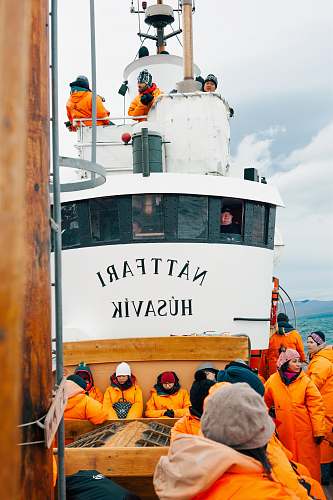 human people on white Nattfari Husavik ship on body of water during cloudy weather hat