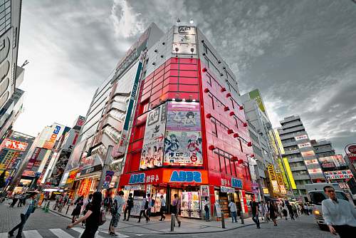 person people walking in front of red high-rise building under gray clouds human