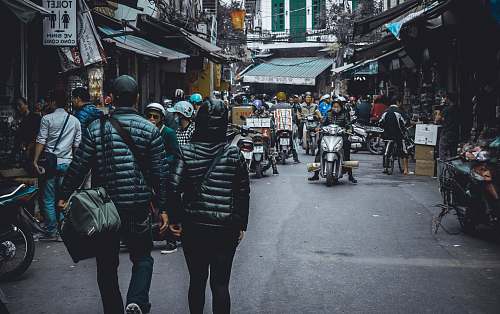 human people walking on the street surrounded by concrete structures motorcycle