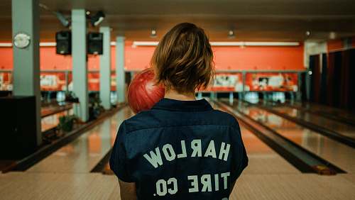 human person holding bowling ball facing bowling pins person