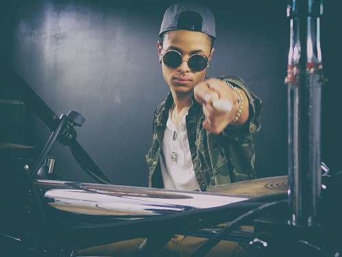 human person holding drumstick seating in front of drum set person