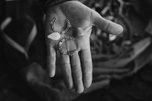 person person holding silver-colored earrings black-and-white