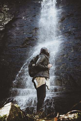human person standing beside waterfalls person