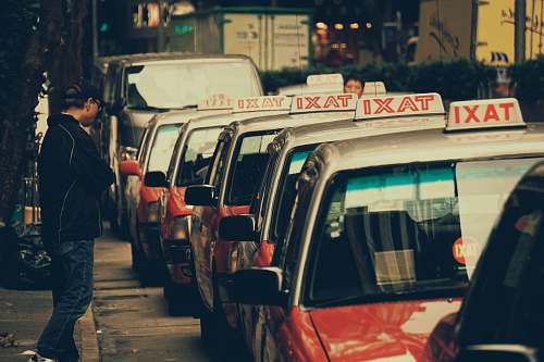 human person standing near parked taxi during daytime person